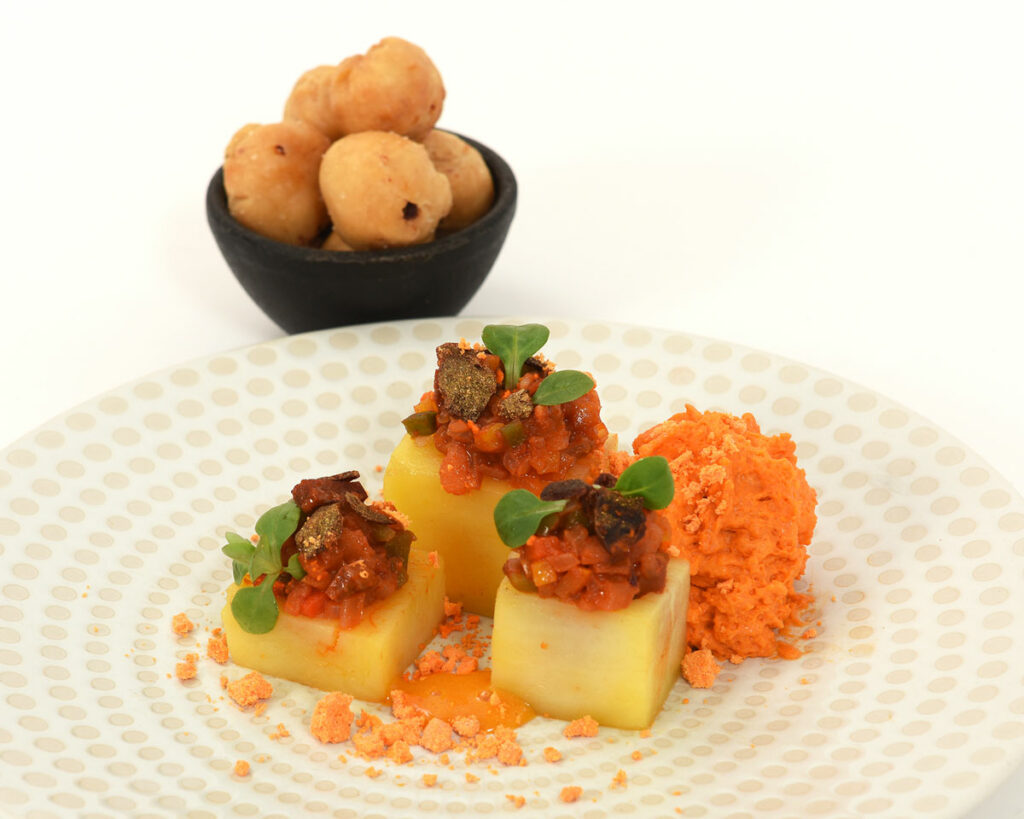Dados de patata confitada rellenas con pisto casero, espuma de dos chorizos, sus chips crujientes y crema de huevo curada